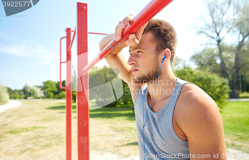 Image of young man with earphones and horizontal bar