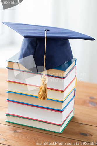 Image of close up of books and mortarboard on wooden table