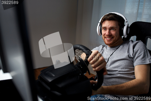 Image of man playing car racing video game at home