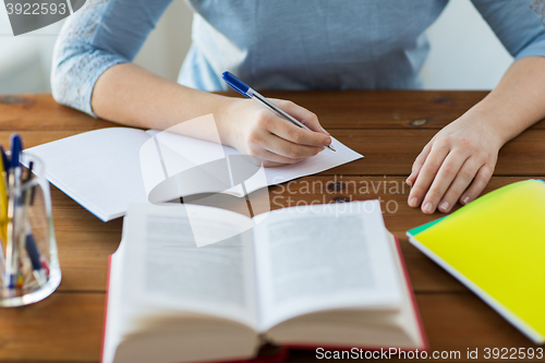 Image of close up of student with book and notebook at home