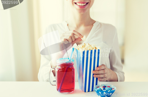 Image of woman eating popcorn with drink in glass mason jar