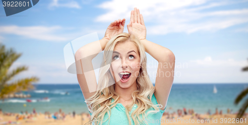 Image of happy smiling young woman making bunny ears