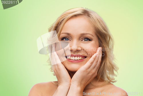 Image of smiling woman with bare shoulders touching face