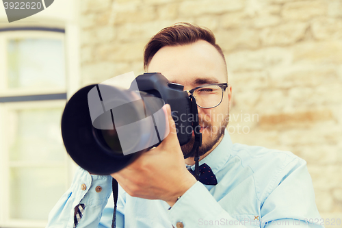 Image of young hipster man with digital camera in city