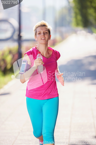 Image of sporty woman running  on sidewalk