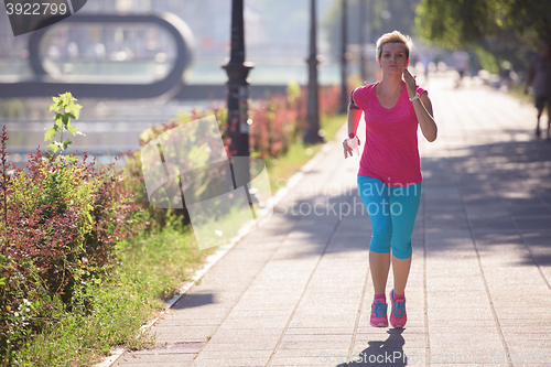 Image of sporty woman running  on sidewalk