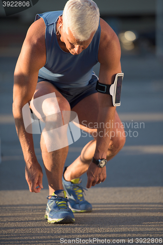 Image of Man tying running shoes laces