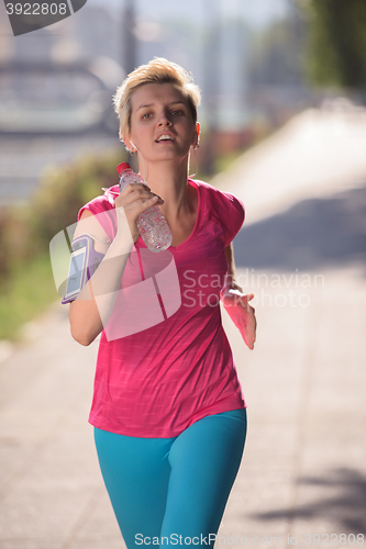 Image of sporty woman running  on sidewalk