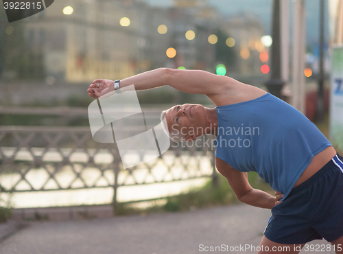 Image of handsome man stretching before jogging
