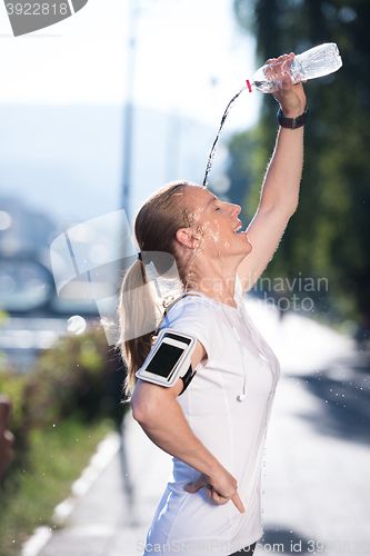 Image of woman drinking  water after  jogging