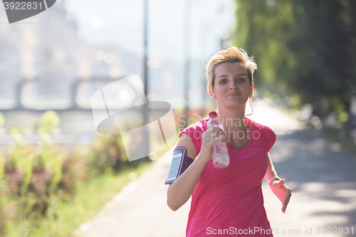 Image of sporty woman running  on sidewalk