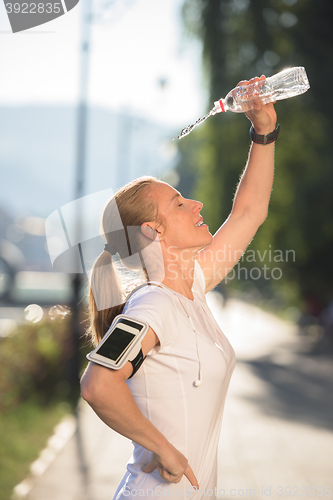 Image of woman drinking  water after  jogging