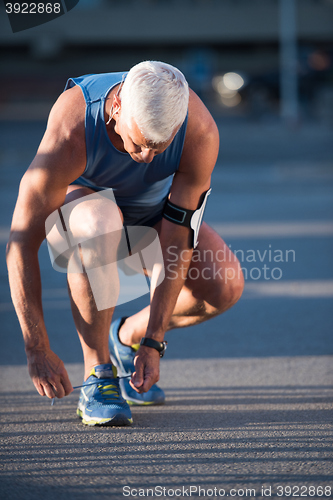 Image of Man tying running shoes laces