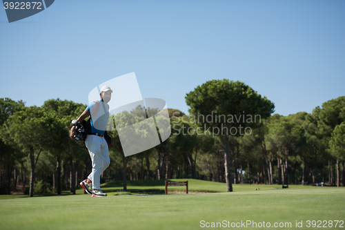 Image of golf player walking and carrying bag