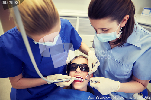 Image of female dentists treating patient girl teeth