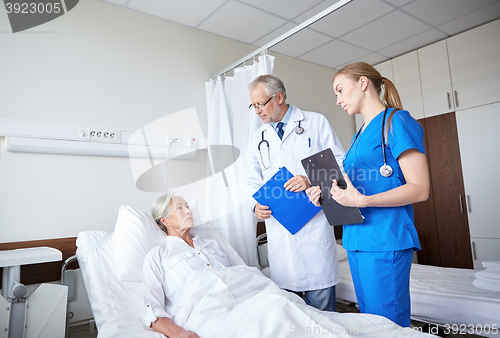 Image of doctor and nurse visiting senior woman at hospital