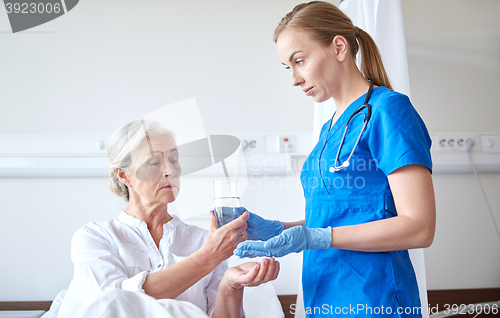 Image of nurse giving medicine to senior woman at hospital