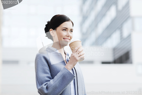 Image of smiling woman drinking coffee in city