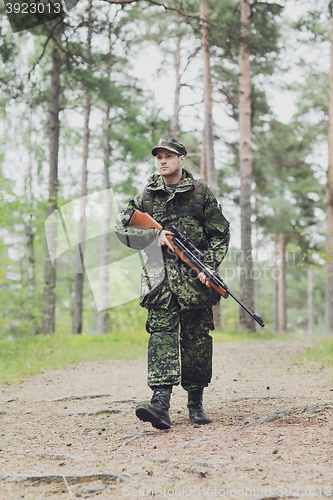 Image of young soldier or hunter with gun in forest