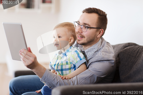 Image of father and son with tablet pc playing at home