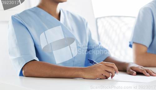 Image of close up of doctor taking notes at hospital