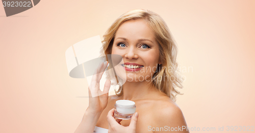 Image of happy woman applying cream to her face