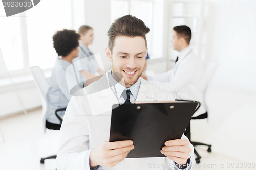 Image of happy doctor with tablet pc over team at clinic