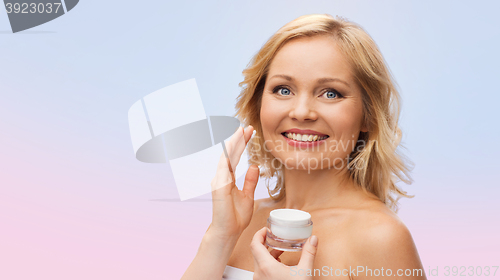 Image of happy woman applying cream to her face