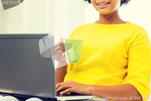 Image of happy african american woman with laptop at home