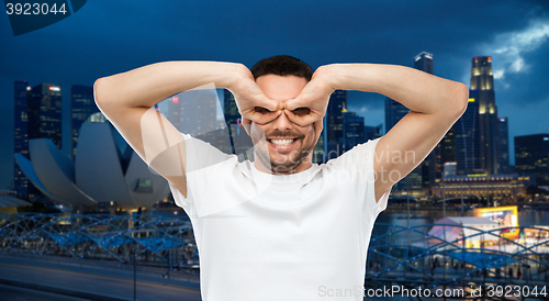 Image of man making finger glasses over city background