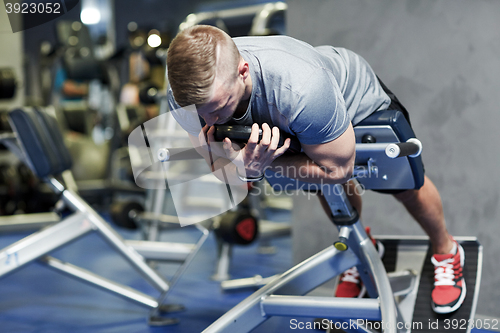 Image of young man flexing back muscles on bench in gym