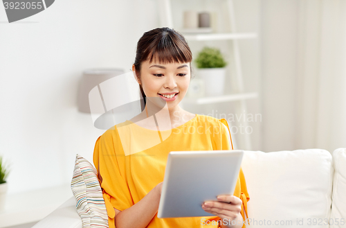 Image of happy young asian woman with tablet pc at home