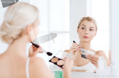 Image of woman with makeup brush and foundation at bathroom