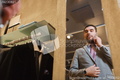 Image of man calling on smartphone at clothing store mirror