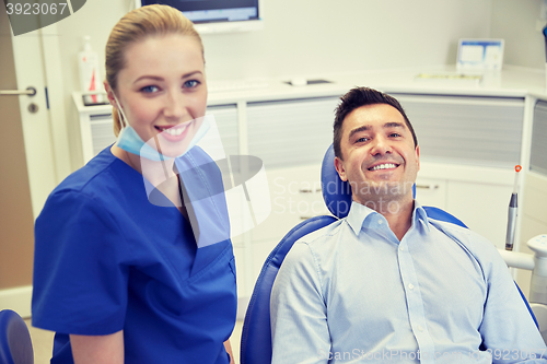 Image of happy female dentist with man patient at clinic