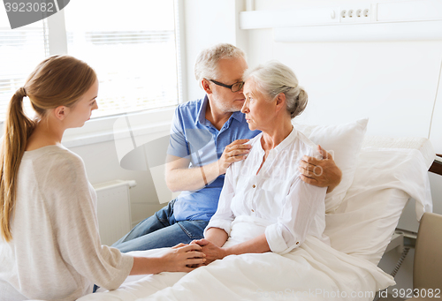 Image of family visiting ill senior woman at hospital