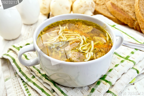 Image of Soup with mushrooms and noodles in bowl on board