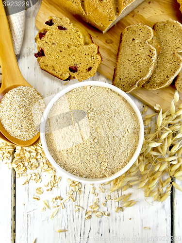 Image of Flour oat in white bowl with bran in spoon on board top