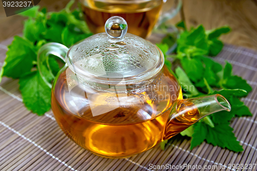 Image of Tea with mint in glass teapot on wooden board
