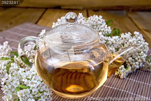 Image of Tea with yarrow in glass teapot on bamboo