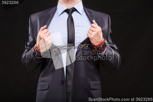 Image of man in a business suit with leather bound with handcuffs. sex Toys