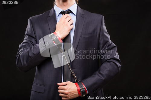 Image of man in a business suit with leather bound with handcuffs. sex Toys