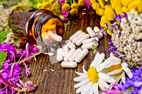Image of Capsules in open brown jar on board with flowers