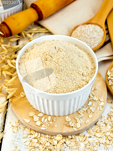 Image of Flour oat in white bowl with bran and flakes on board