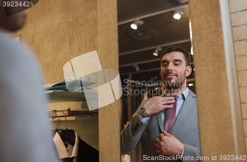 Image of man trying tie on at mirror in clothing store