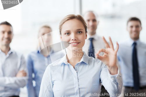 Image of smiling businesswoman showing ok sign in office