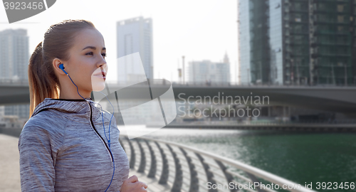 Image of happy woman with earphones running over dubai city