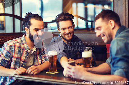 Image of male friends with smartphone drinking beer at bar