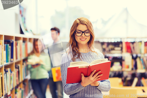 Image of happy student girl or woman with book in library