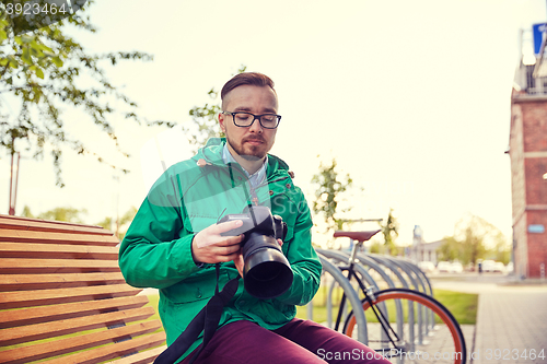 Image of young hipster man with digital camera in city